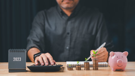 Businessman calculates coins tower stacked on desk wood, Business finance and saving money...