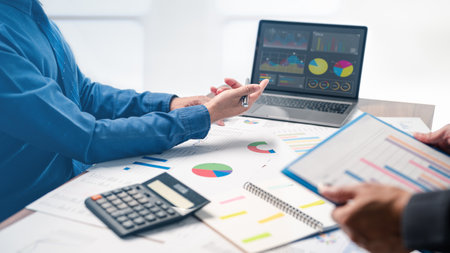 The businessman is pointing to the financial report while brainstorming with his team on a successful plan for their upcoming project, as they work together on the necessary paperwork and planning.の写真素材