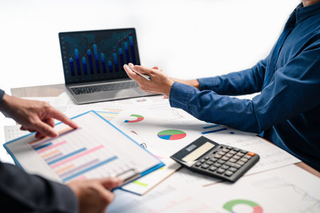 The businessman is pointing to the financial report while brainstorming with his team on a successful plan for their upcoming project, as they work together on the necessary paperwork and planning.の写真素材