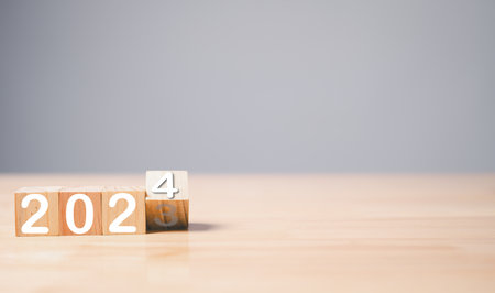 A startup founder flips a wooden cube with the year 2024 on it to symbolize the change of the year...