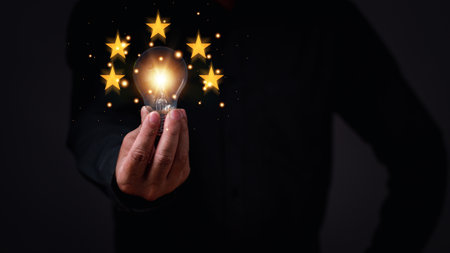 businessman holding a light bulb concept of global business to driven startup with five stars success. Bright lights give hope to small businesses. invention, finance, Copy space, black backgroundの写真素材