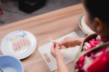 Close-up of an Asian woman&#39;s hands preparing fresh, natural ingredients for a healthy meal in a cozy home kitchen.の写真素材