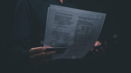 A person is holding a credit card and a piece of paper. The paper has numbers on it