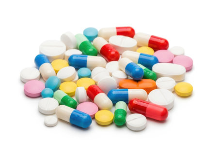 A large pile of diverse pharmaceutical pills and capsules in various colors and shapes, isolated on a clean white background.の素材