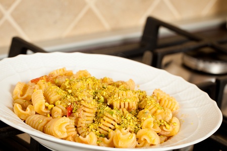 A dish of pasta with salmon, tomatoes and pistachios nutsの写真素材
