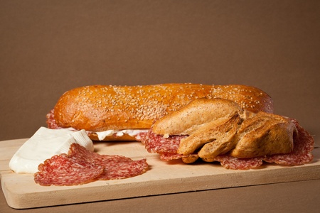 Two sandwiches wit italian sliced salami and fresh cheese over a wooden boardの写真素材