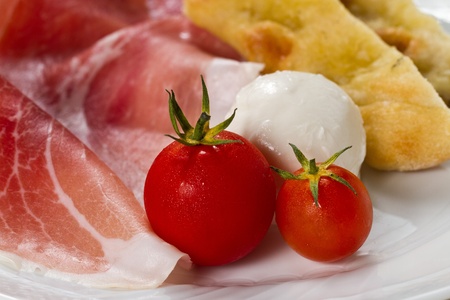 Dish with typical Italian food. Raw ham, mozzarella cheese, cherry tomatoes and focaccia pizzaの写真素材