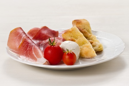 Dish with typical Italian food. Raw ham, mozzarella cheese, cherry tomatoes and focaccia pizzaの写真素材