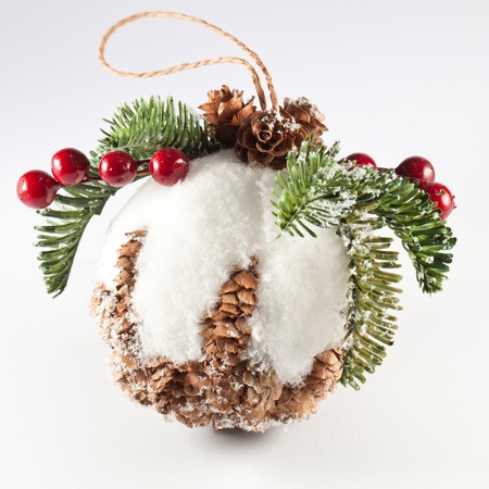 Pine cone christmas ball whit leaves, snow and berry on top. Isolated studio shot with white backgroundの写真素材