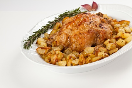 Roast chicken with potato in a white dish decorated with garlic and rosemary. Isolated studio shotの写真素材
