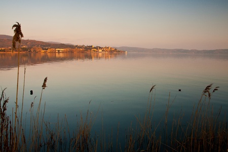View of Trasimeno lake and small village of Passignano with golden sunset lightの写真素材