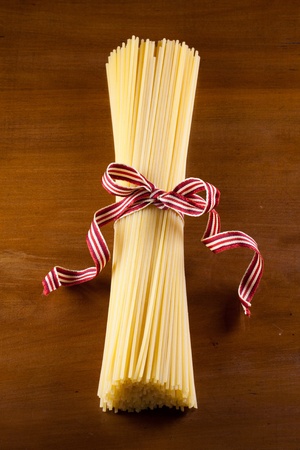 fine raw spaghetti pasta tighten with cotton ribbon over an antique wood tableの写真素材