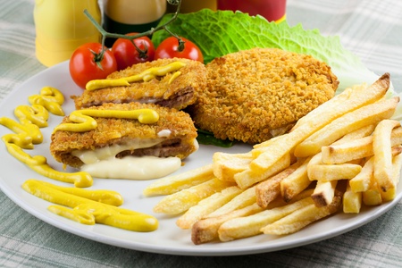 Delicious cordon bleu with melting cheese and french fries. Garnished with mustard, tomatoes and...