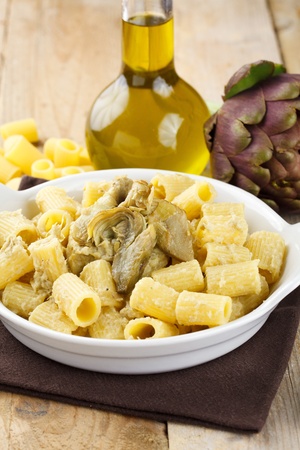 Dish of pasta with artichoke. Traditional Italian recipe. Served in a white terrine and decorated with fresh artichoke, olive oil and raw pastaの写真素材