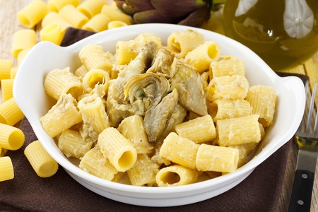 Dish of pasta with artichoke. Traditional Italian recipe. Served in a white terrine and decorated with fresh artichoke, olive oil and raw pastaの写真素材