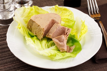 Chunk of tuna fish in a lettuce bed, served in an elegant place settingの写真素材