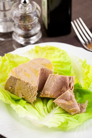 Chunk of tuna fish in a lettuce bed, served in an elegant place settingの写真素材