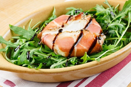 Tomino soft cheese in a bacon wrap, topped with balsamic vinegar, over an rocket bedの写真素材