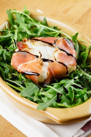 Tomino soft cheese in a bacon wrap, topped with balsamic vinegar, over an rocket bedの写真素材