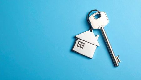 House key on blue background with copy space. Real estate concept.の素材