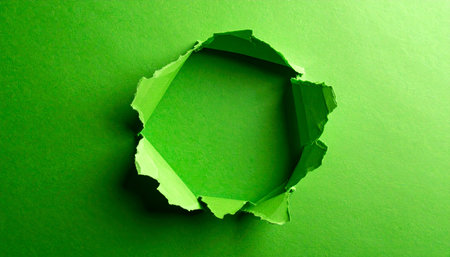 A jagged, geometric hole is torn in bright green paper, revealing a textured background.の素材