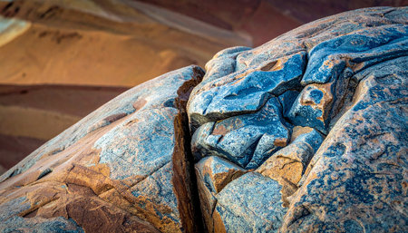 A close-up of a cracked blue and orange rock surface revealing a deep fissure and layered mineral veins.の素材