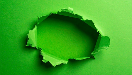 A rough, torn hole in green paper reveals a bright green inner surface with textured edges.の素材