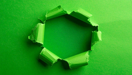 A torn hole in bright green paper reveals a deeper green background with ragged, torn edges.の素材
