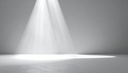 A single bright spotlight beam shines down onto a textured stage floor, casting a soft, elongated shadow.の素材