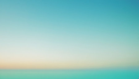 A soft turquoise sea meets a pale blue sky, with a gentle gradient and a subtle warm horizon.の素材