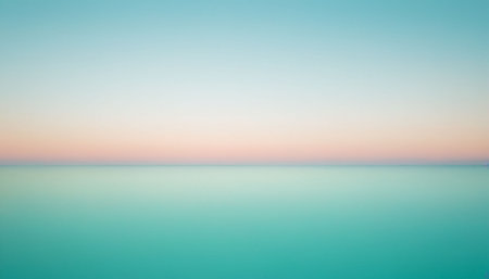 A minimalist horizon line separates a soft pastel sky with pink and peach tones from a vast expanse of turquoise...の素材