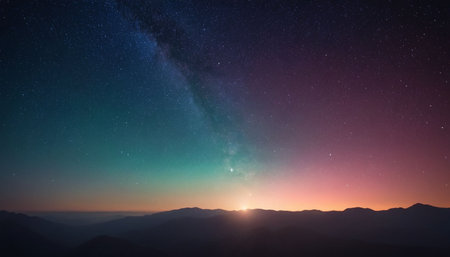 The Milky Way galaxy arcs across a deep blue and purple night sky, with a dark mountain range silhouetted against...の素材