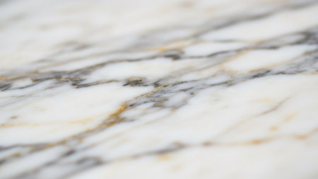 Close-up view of a white marble surface featuring delicate grey and golden veins with a shallow depth of field.の素材