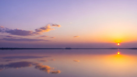 Body showing serene sunset over a calm body of water reflecting the orange and purple sky. resolutionの素材