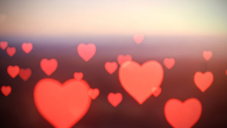 Numerous soft red heart shapes are scattered across a warm sunset sky and dark foreground creating a romantic bokeh...の素材