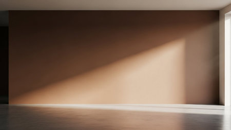 An empty room a large brown wall with a long diagonal shadow cast by bright sunlight from a window.の素材