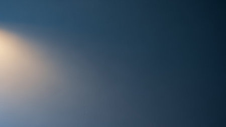 A smooth gradient transitions from deep blue to lighter teal, with a soft warm light source subtly illuminating the...の素材