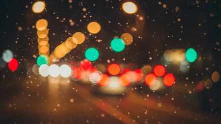 Soft focus bokeh lights in red, green, and yellow from traffic signals, with falling snowflakes creating a magical...の素材