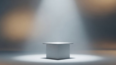 A clean white cube pedestal sits centered under a bright spotlight, with a softly blurred, neutral background.の写真素材