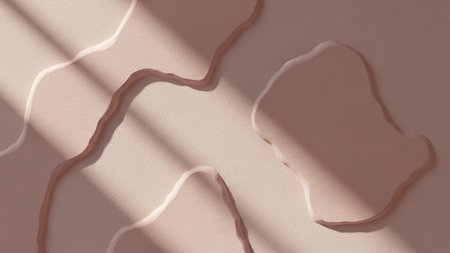 A soft pink textured surface organic abstract shapes and is dramatically lit by diagonal sunlight casting distinct...の写真素材