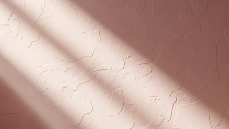 A textured rose pink wall surface with soft sunlight casting dappled shadow patterns, creating a warm and inviting...の写真素材