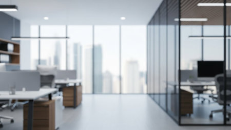 A blurred view of a modern office interior with glass walls, desks, and a city skyline visible through windows.の素材
