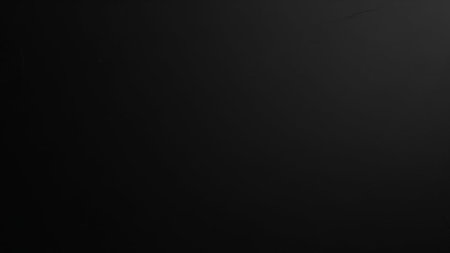 A completely solid, deep black background with a very subtle, almost imperceptible texture, offering ample negative...の素材