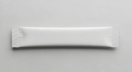 A blank white single serving stick sachet with textured ends is centered on a light gray background, ready for branding.の素材