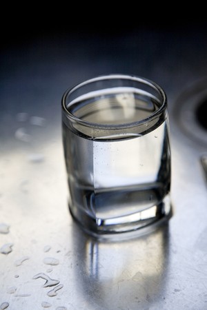 Glass of water on a kitchen sinkの写真素材