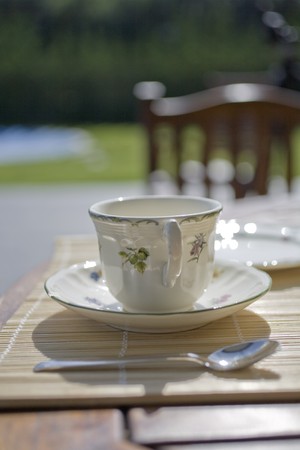 Tea cup with a saucer on a table in a gardenの写真素材