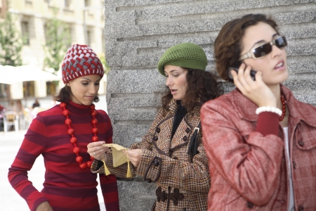 Young latin woman talking on th mobile phone while other two friends chat in the back.の写真素材