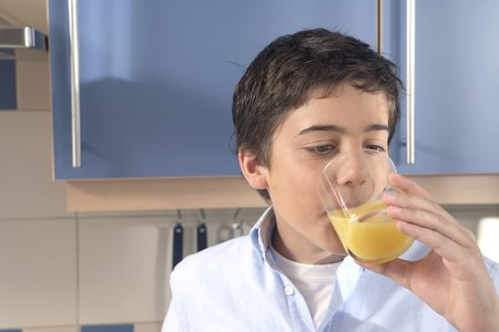 12-15 years old boy drinking a glass of orangeの写真素材