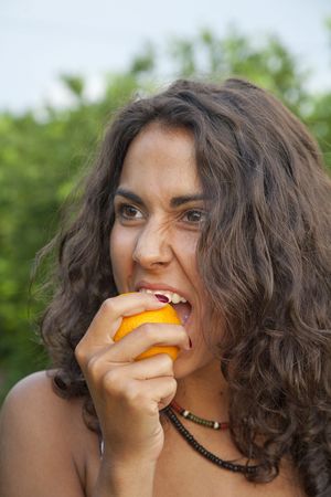 Young Latin Woman eating orange directly from the tree, Valencia, Spainの写真素材