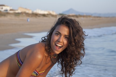 Young pretty woman by the beach, wearing orange sarong.の写真素材